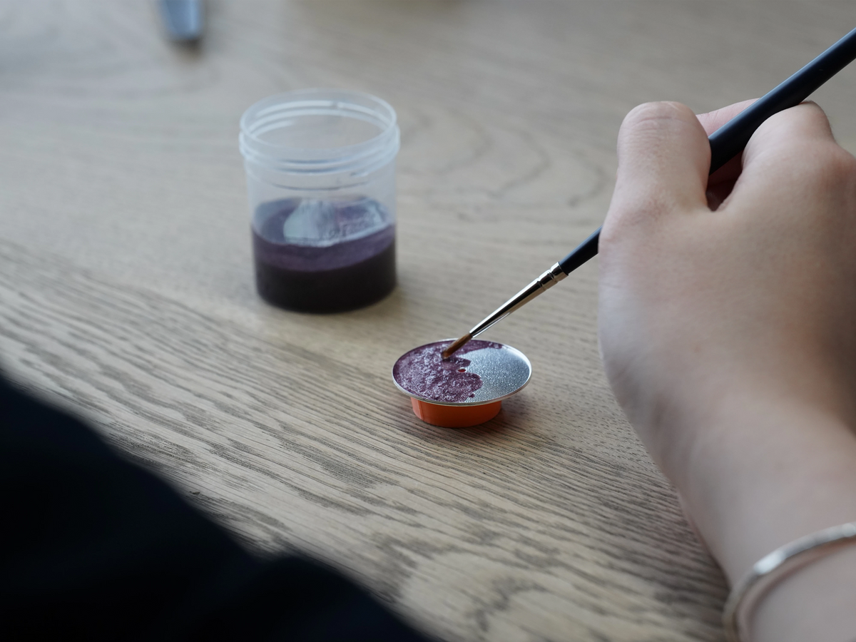 An anOrdain craftsperson applying vitreous enamel to a dial
